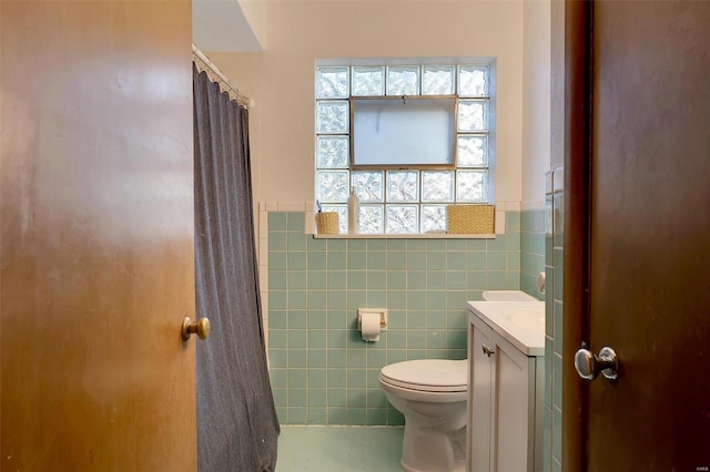 bathroom with a shower with shower curtain, vanity, toilet, and tile walls