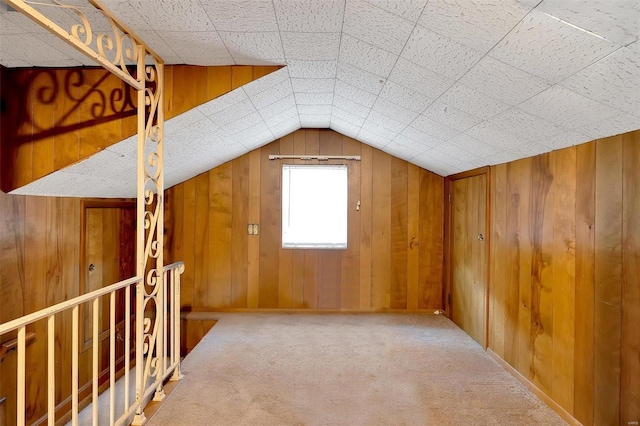 bonus room with wooden walls, carpet floors, and lofted ceiling