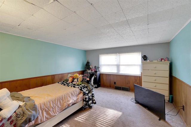 bedroom with light colored carpet and wooden walls