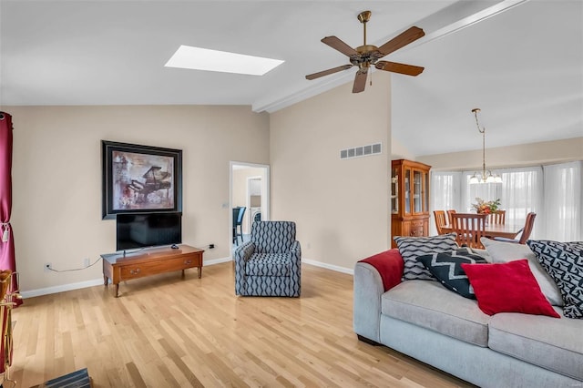 living room with vaulted ceiling with skylight, light hardwood / wood-style floors, and ceiling fan with notable chandelier