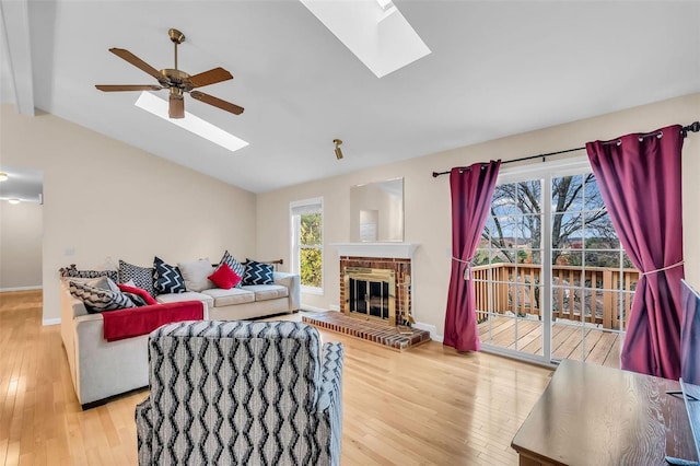 living room with vaulted ceiling with beams, plenty of natural light, light hardwood / wood-style floors, and a fireplace