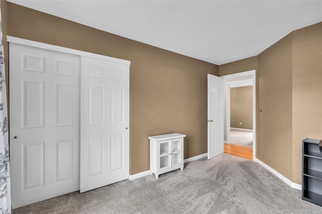 unfurnished bedroom with light colored carpet and a closet