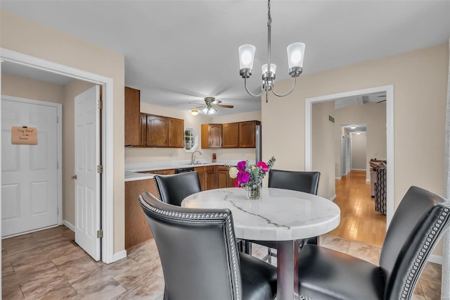 dining space with ceiling fan with notable chandelier, light hardwood / wood-style floors, and sink