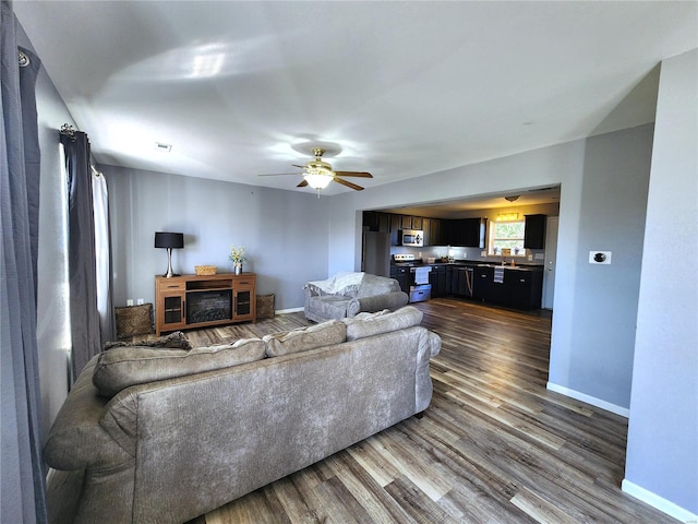 living room featuring ceiling fan and dark wood-type flooring