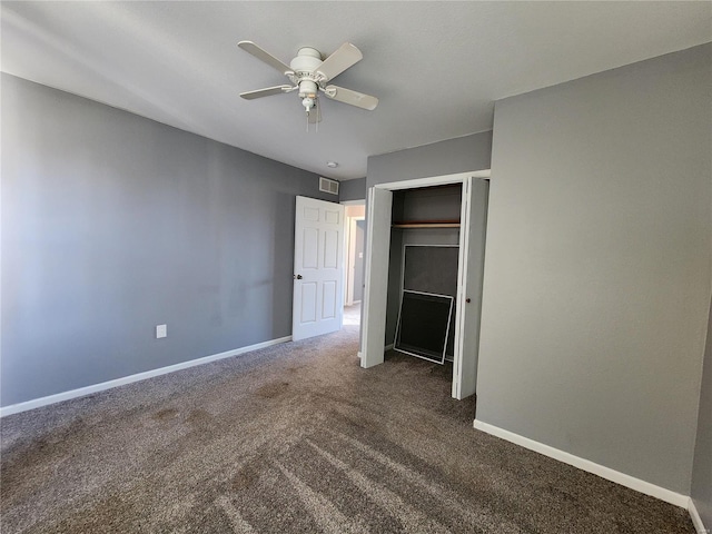 unfurnished bedroom with ceiling fan, dark carpet, and a closet