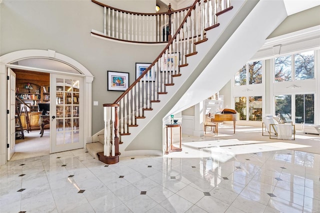 tiled foyer with a towering ceiling and french doors