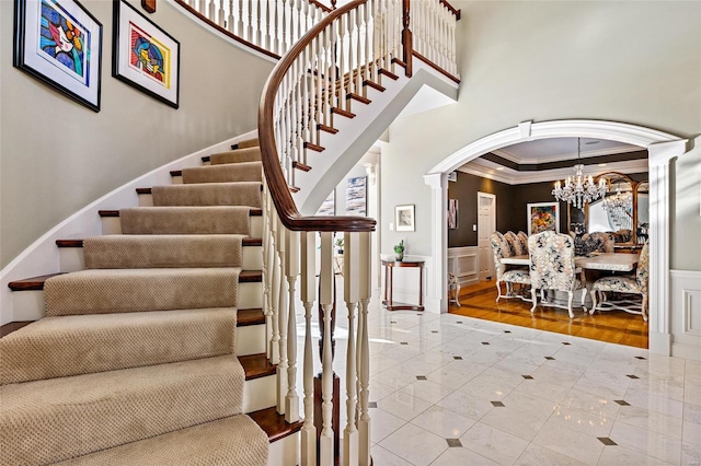 staircase featuring hardwood / wood-style flooring, crown molding, and a notable chandelier