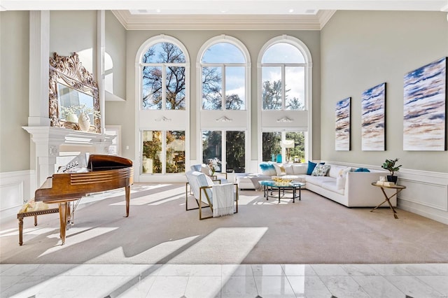 living room featuring a towering ceiling, crown molding, and a wealth of natural light