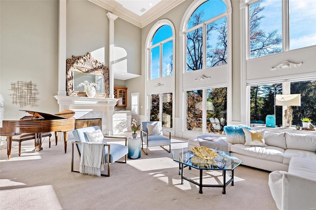 carpeted living room featuring a high end fireplace, a wealth of natural light, crown molding, and a towering ceiling