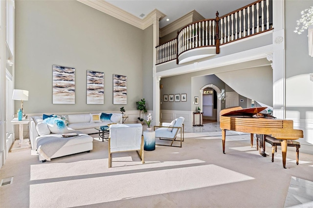 carpeted living room with a towering ceiling and ornamental molding