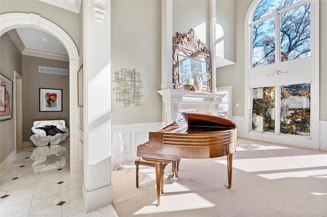 sitting room featuring a high ceiling, light tile patterned floors, and ornamental molding