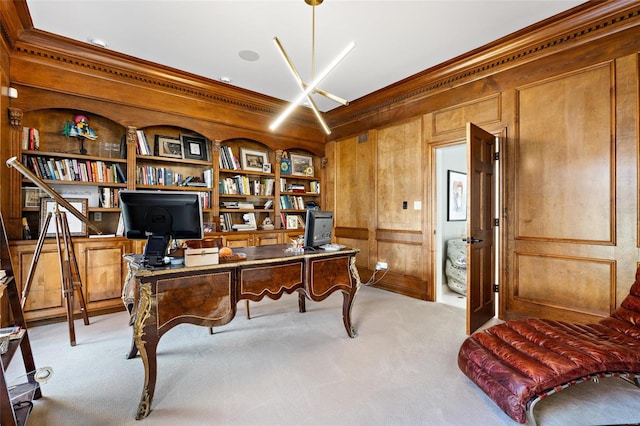 carpeted home office featuring built in shelves, wood walls, and ornamental molding