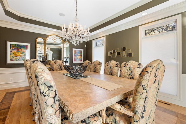 dining area featuring light hardwood / wood-style floors, ornamental molding, a tray ceiling, and an inviting chandelier