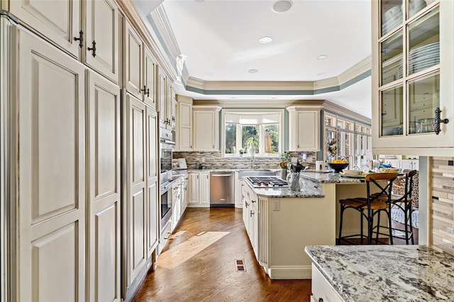 kitchen featuring a center island, light hardwood / wood-style flooring, light stone countertops, ornamental molding, and cream cabinetry