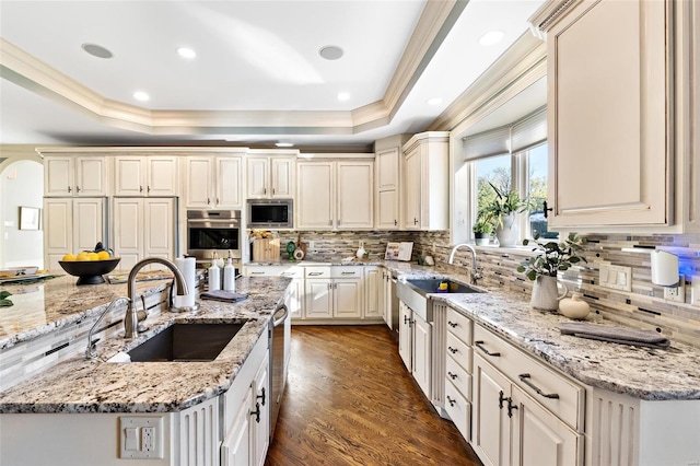 kitchen featuring backsplash, light stone counters, sink, and appliances with stainless steel finishes