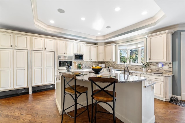 kitchen featuring appliances with stainless steel finishes, dark hardwood / wood-style flooring, a center island with sink, and light stone counters