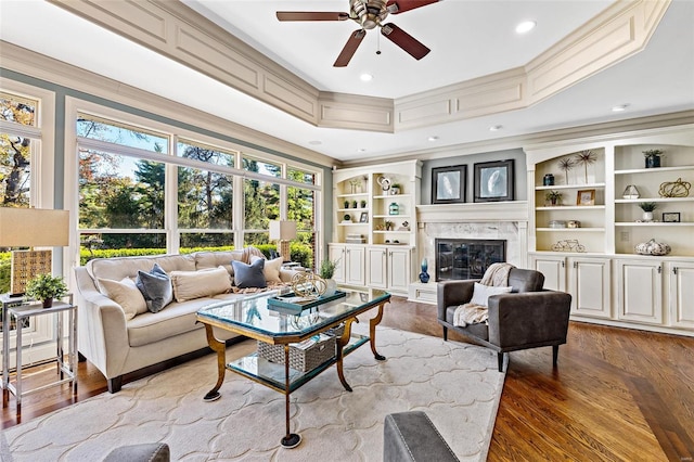 living room featuring ceiling fan, a high end fireplace, ornamental molding, and hardwood / wood-style flooring