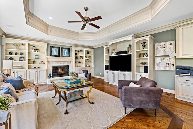 living room with ceiling fan, a high end fireplace, wood-type flooring, and ornamental molding