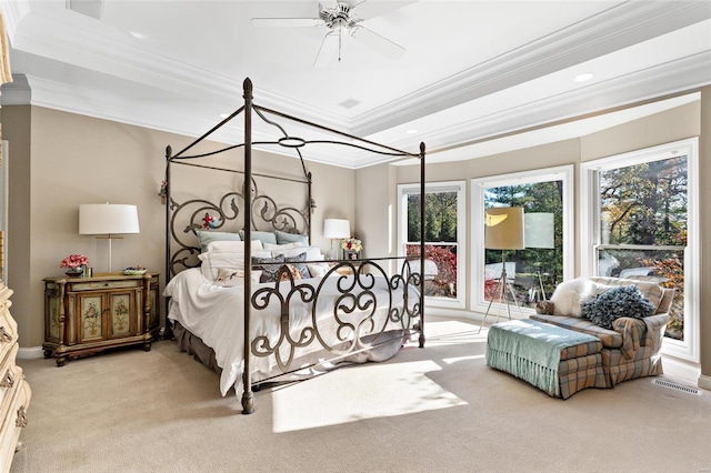 bedroom with light colored carpet, ceiling fan, crown molding, and a tray ceiling