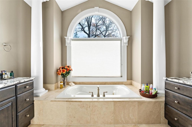 bathroom with vanity, decorative columns, lofted ceiling, and tiled tub