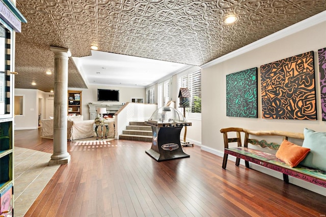 living room with wood-type flooring, ornate columns, and crown molding