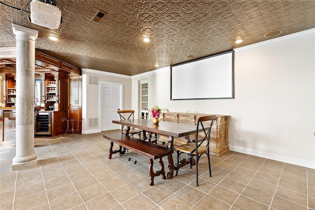 dining space with wine cooler, ornate columns, ornamental molding, and light tile patterned flooring