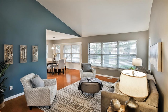 living room featuring wood-type flooring, high vaulted ceiling, a healthy amount of sunlight, and a notable chandelier