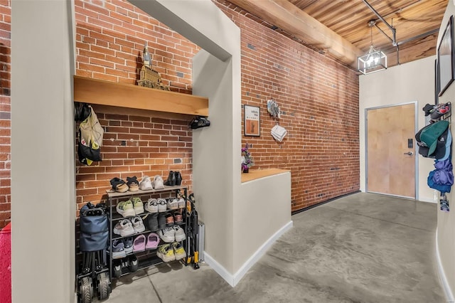 hall featuring concrete flooring, brick wall, and wooden ceiling