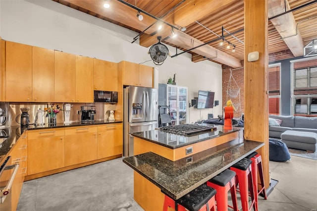 kitchen featuring stainless steel appliances, a high ceiling, dark stone countertops, a breakfast bar, and a kitchen island