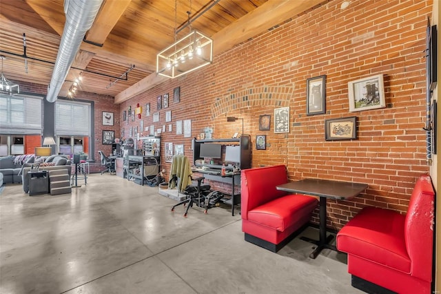 office area with brick wall, beam ceiling, wooden ceiling, a high ceiling, and concrete floors