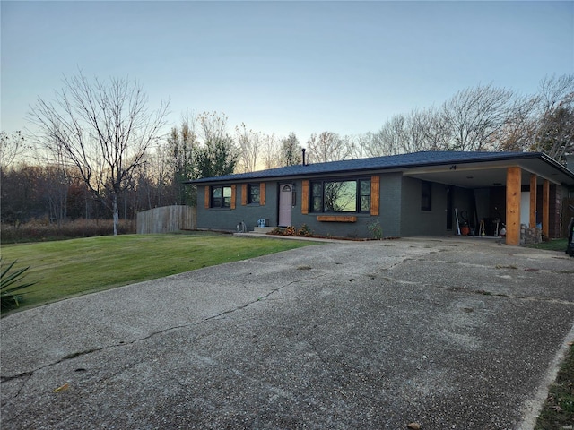 ranch-style house featuring a carport and a yard