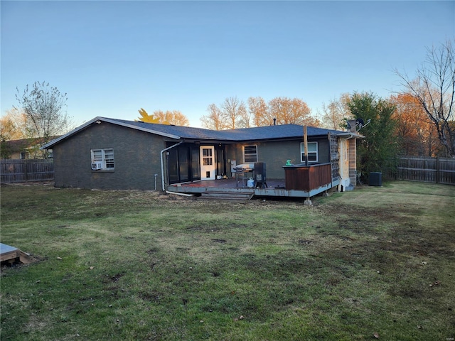 rear view of property with a sunroom, central air condition unit, a wooden deck, and a lawn