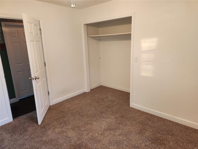 unfurnished bedroom featuring a closet and dark colored carpet