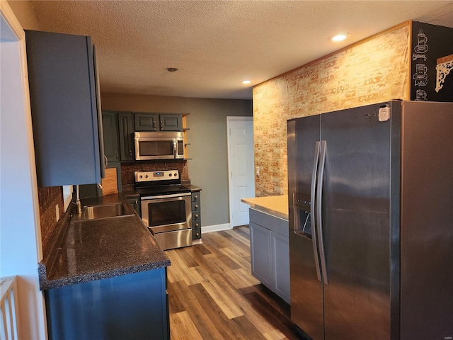 kitchen featuring a textured ceiling, sink, stainless steel appliances, and dark hardwood / wood-style floors