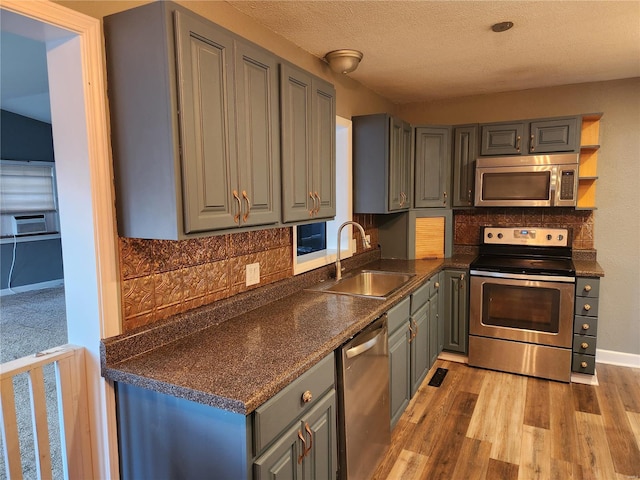 kitchen with sink, stainless steel appliances, tasteful backsplash, hardwood / wood-style floors, and a textured ceiling