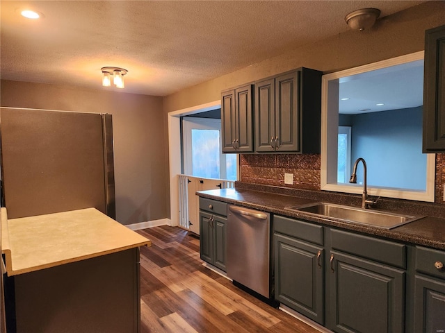 kitchen featuring tasteful backsplash, a textured ceiling, dark wood-type flooring, sink, and dishwasher