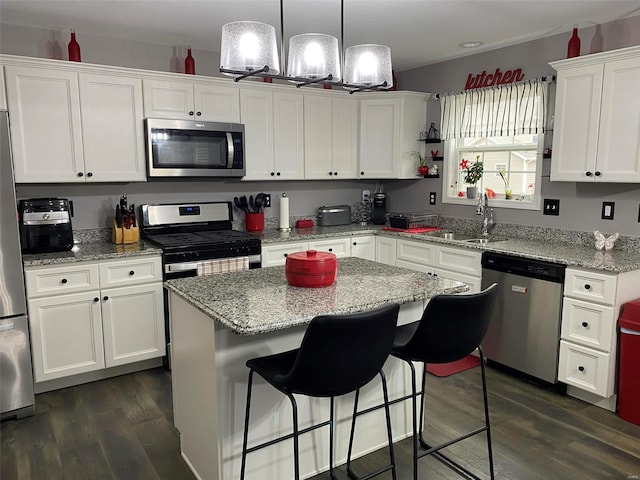 kitchen with stainless steel appliances, dark wood-type flooring, sink, a center island, and white cabinetry