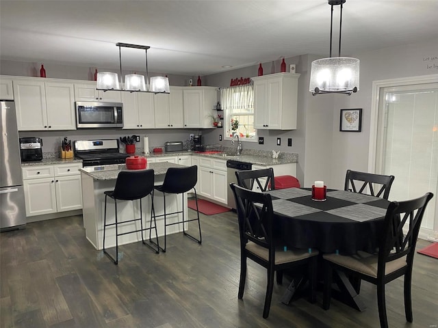 kitchen featuring white cabinets, a kitchen island, hanging light fixtures, and appliances with stainless steel finishes