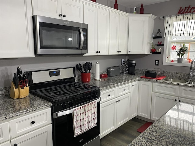 kitchen with light stone countertops, white cabinetry, sink, dark wood-type flooring, and appliances with stainless steel finishes