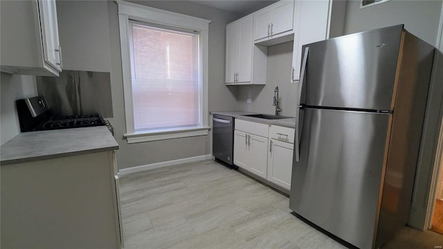 kitchen featuring appliances with stainless steel finishes, white cabinetry, and sink