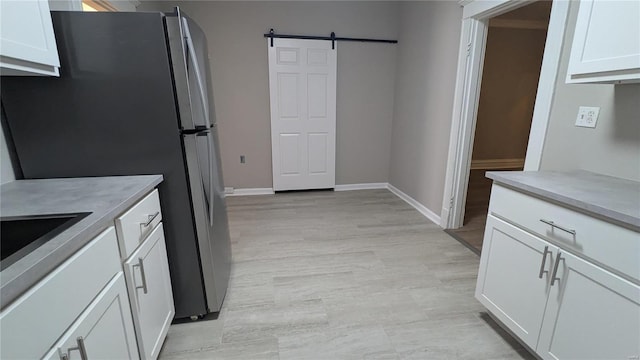 kitchen with white cabinets, stainless steel fridge, and a barn door