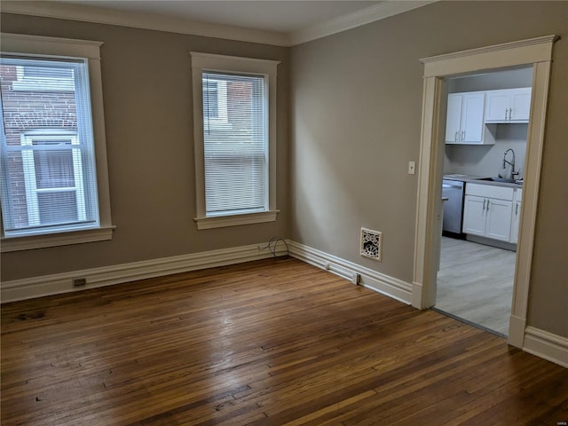 spare room featuring a healthy amount of sunlight, sink, ornamental molding, and dark wood-type flooring