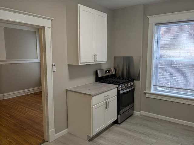 kitchen with gas range, white cabinetry, and light hardwood / wood-style floors