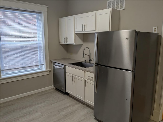 kitchen featuring white cabinets, light hardwood / wood-style floors, sink, and appliances with stainless steel finishes