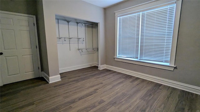 unfurnished bedroom featuring multiple windows, a closet, and dark hardwood / wood-style floors