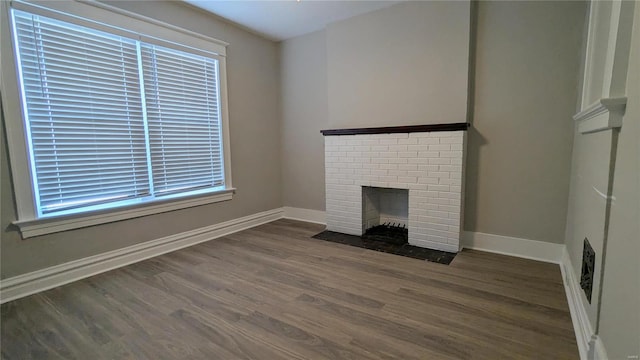 unfurnished living room with a fireplace, a wealth of natural light, and dark wood-type flooring