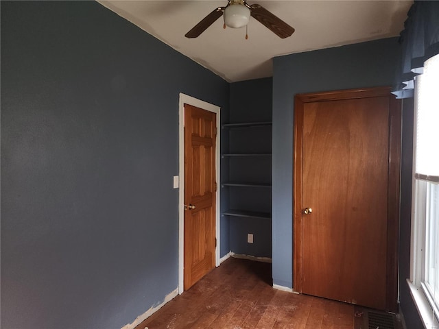 unfurnished bedroom featuring ceiling fan and dark wood-type flooring