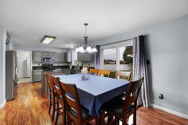 dining area with light wood-type flooring and an inviting chandelier