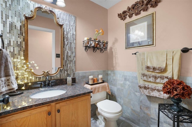 bathroom featuring vanity, toilet, and tile walls