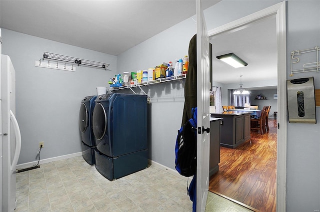 washroom featuring light hardwood / wood-style flooring, washer and clothes dryer, and a notable chandelier